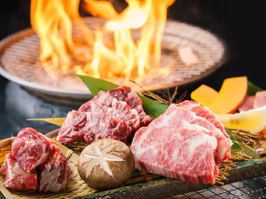 Sizzling barbecue with marbled beef steaks, mushrooms, and colorful vegetables on a grill, flames in the background.