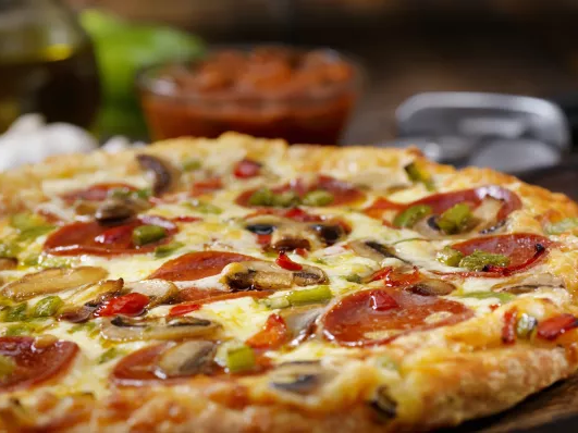 A freshly baked pizza topped with pepperoni, mushrooms, olives, peppers, and melted cheese on a crispy crust.