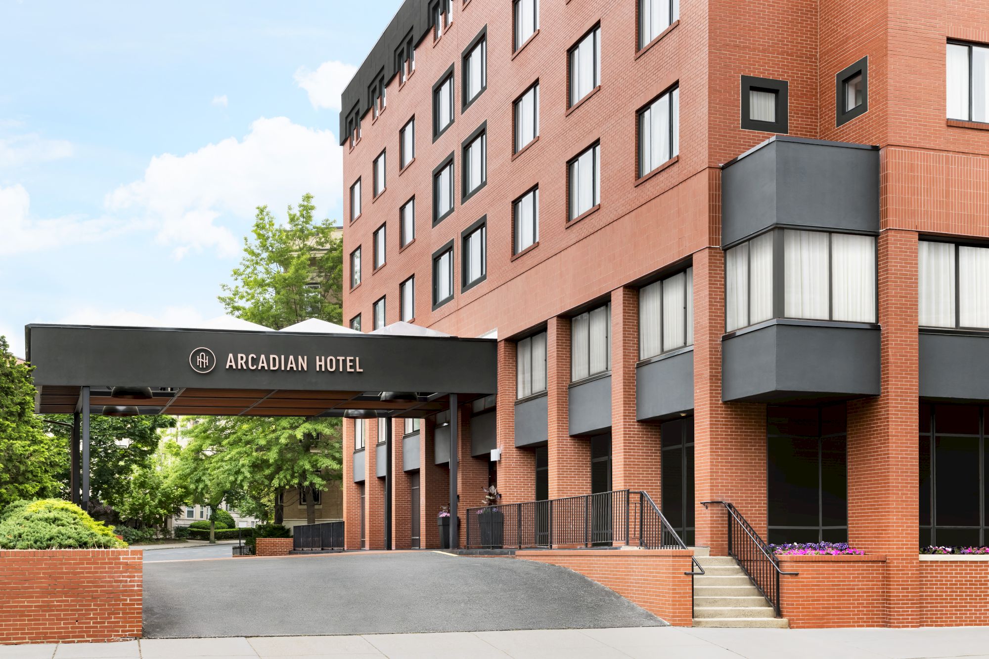 A red-brick hotel building with a portege reading &ldquo;Arcadian Hotel&rdquo; under a bright sky.