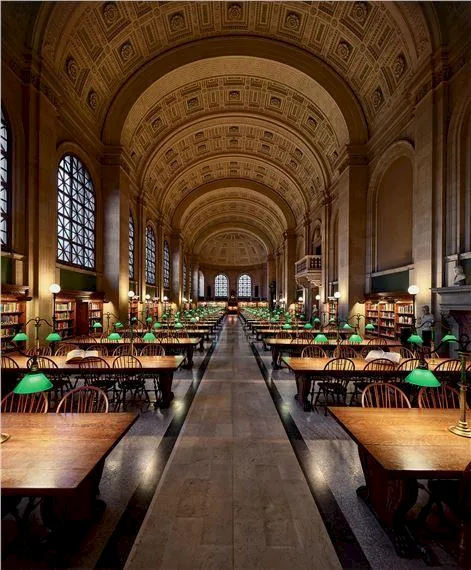 A grand historic hall with vaulted arches, long wooden tables, and green-shaded lamps creating a library-like atmosphere.